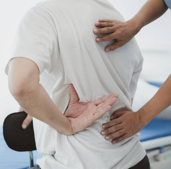 Person holding lower back in pain, illustrating back pain discomfort and seeking relief